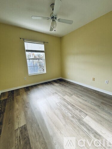 A room with a ceiling fan and a window with blinds.