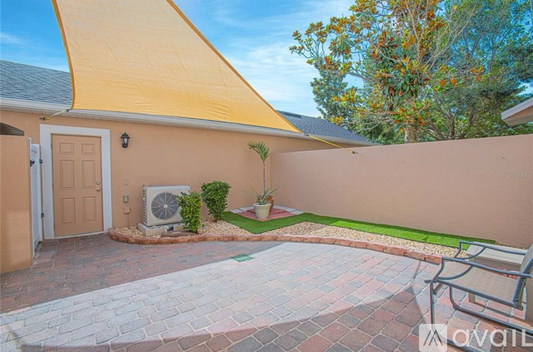 A wet street with a tree and a monument in the background.