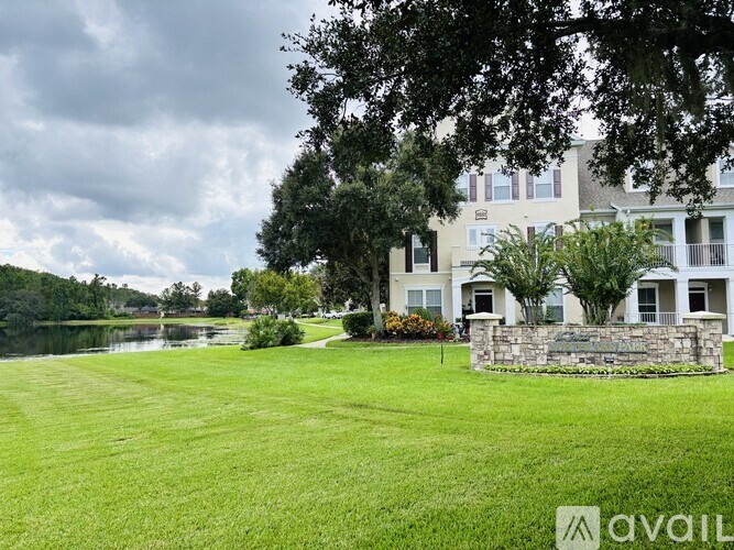 A large grassy area in front of a building with a stone wall and a sign that says "AVAIL".