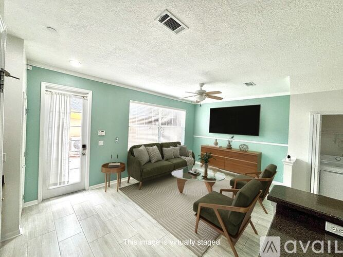 A living room with a couch, chairs, and a television.