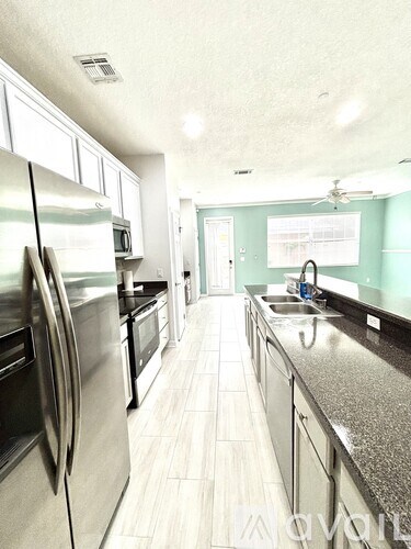 A kitchen with a refrigerator, sink, and stove.