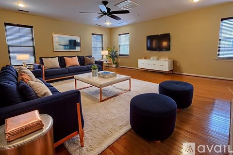 A living room with a dark blue couch, a white coffee table, and a television on the wall.
