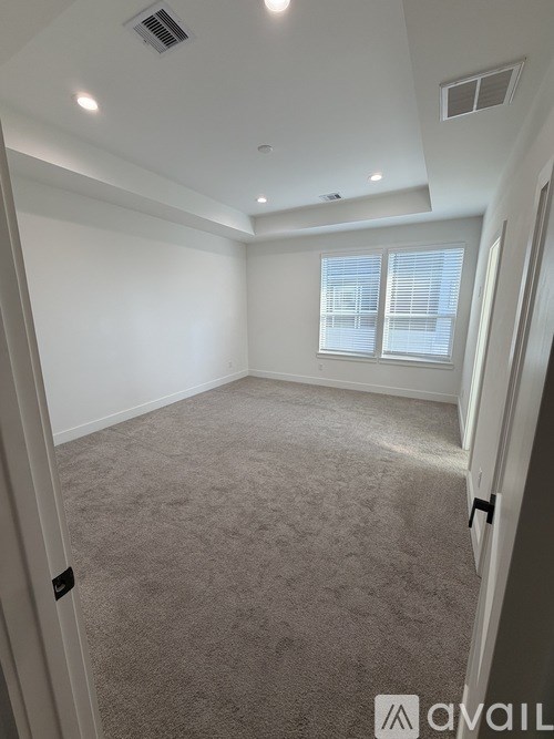 A carpeted room with a window and a door.