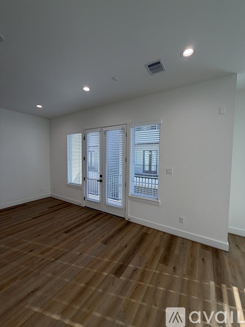 A room with wooden flooring and a window with blinds.