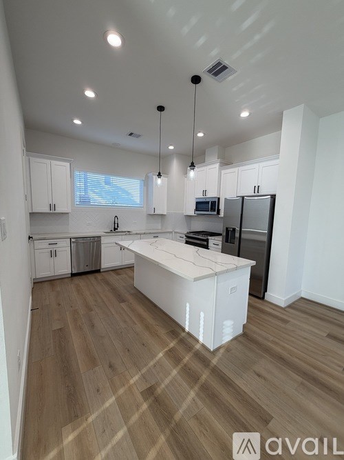 A kitchen with wooden floors and white cabinets.