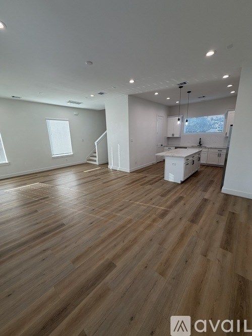 A spacious room with wooden flooring and white walls.