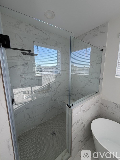 A bathroom with a marble wall and a glass shower door.