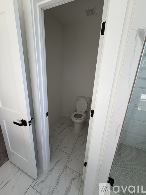 A white door is open to a small bathroom with a toilet.