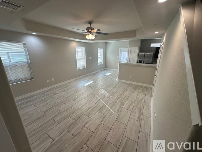 A spacious room with a ceiling fan and lighting fixture.