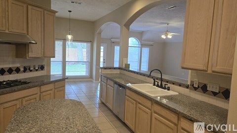 A kitchen with granite countertops and wooden cabinets is available for rent.