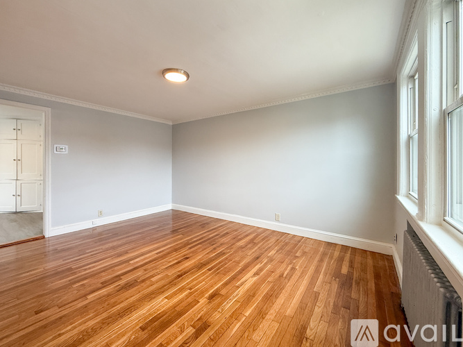 A room with wooden flooring and a window on the right side.
