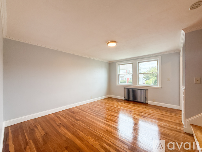 A room with wooden floors and a window with a view of a building outside.
