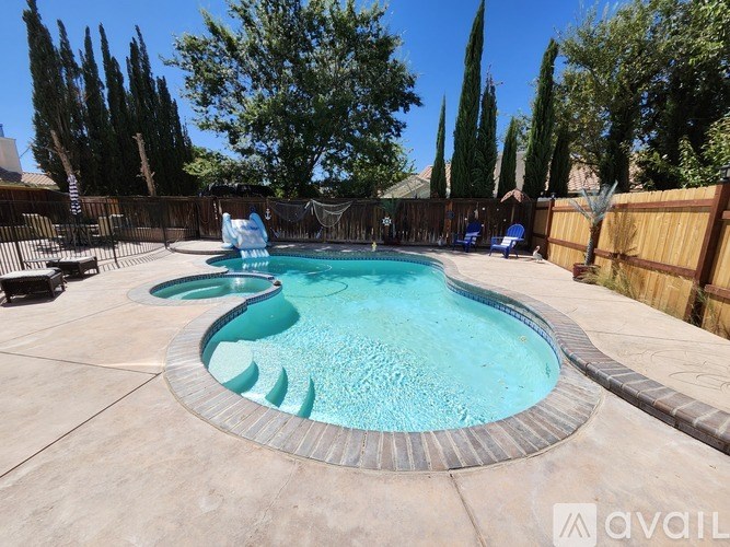 A pool surrounded by a wooden fence and trees.