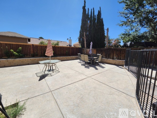 A patio with a table and chairs is surrounded by a fence.