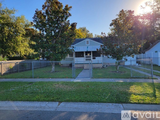 A house with a white fence and a tree in front of it.