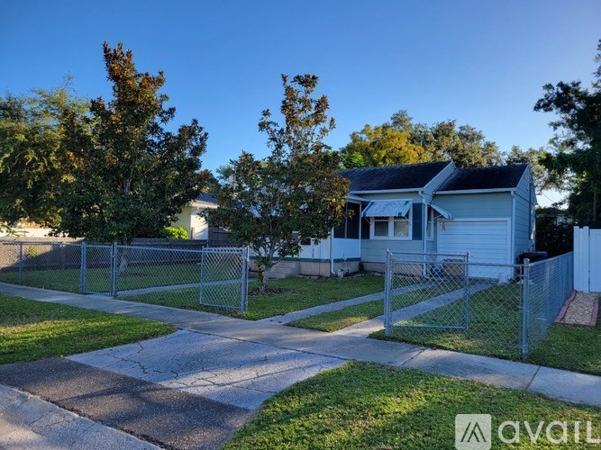 A house with a fence and a tree in front of it.