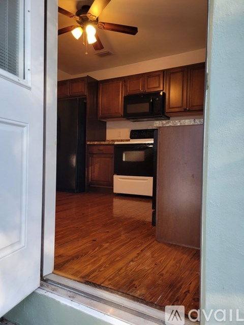A kitchen with wooden cabinets and a black refrigerator.