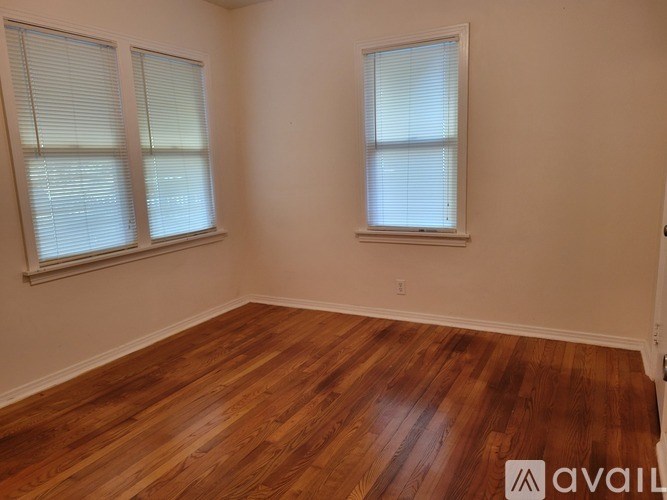 A room with wooden floors and two windows.