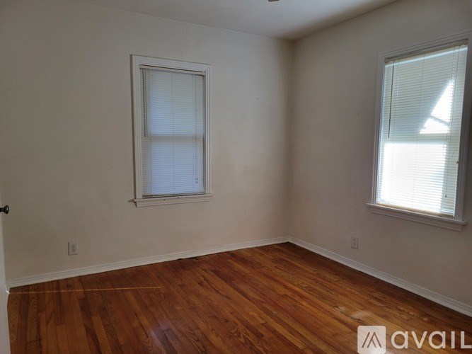 A room with wooden floors and two windows.