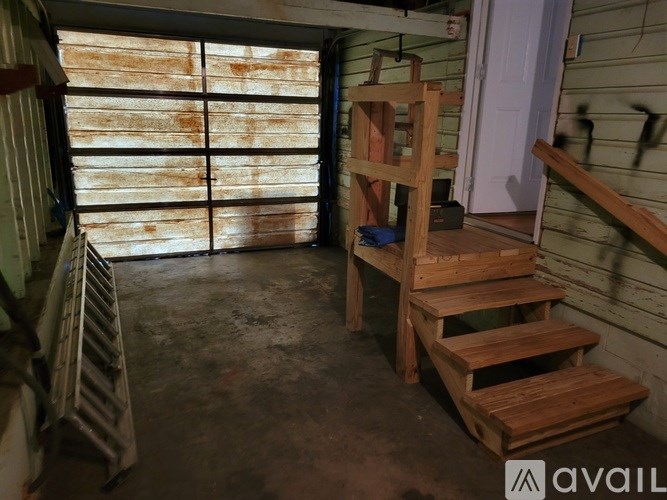 A wooden chair is in the corner of a room with a window covered in dust.