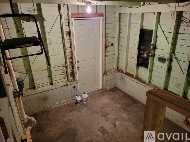 A room with a white door and a ladder against the wall.