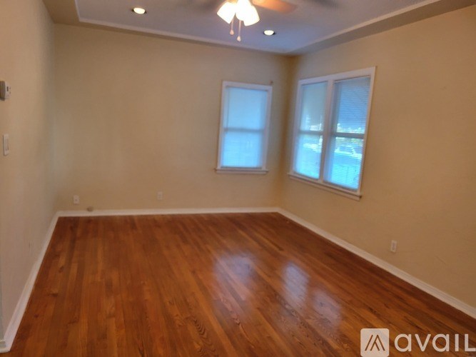 A room with wooden floors and two windows.