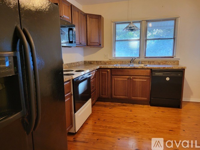 A kitchen with a black fridge, white stove, and wooden cabinets.