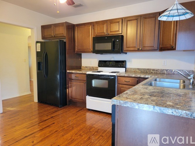 A kitchen with a black refrigerator, black microwave, and black stove.