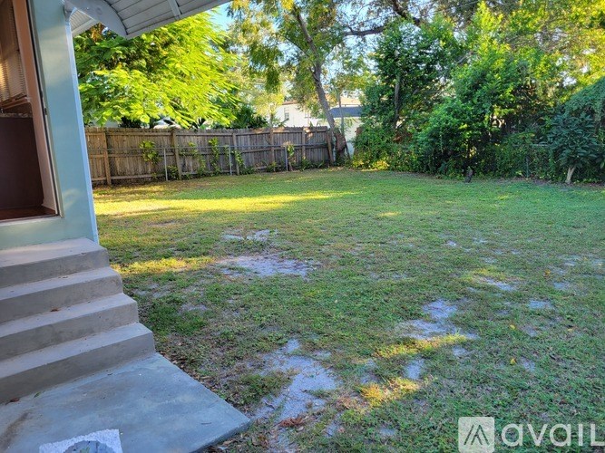 A backyard with a wooden fence and green grass.