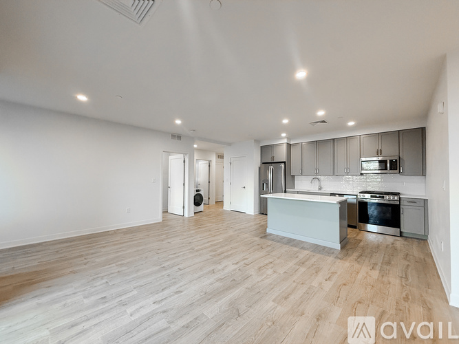 A modern kitchen with wooden floors and stainless steel appliances.