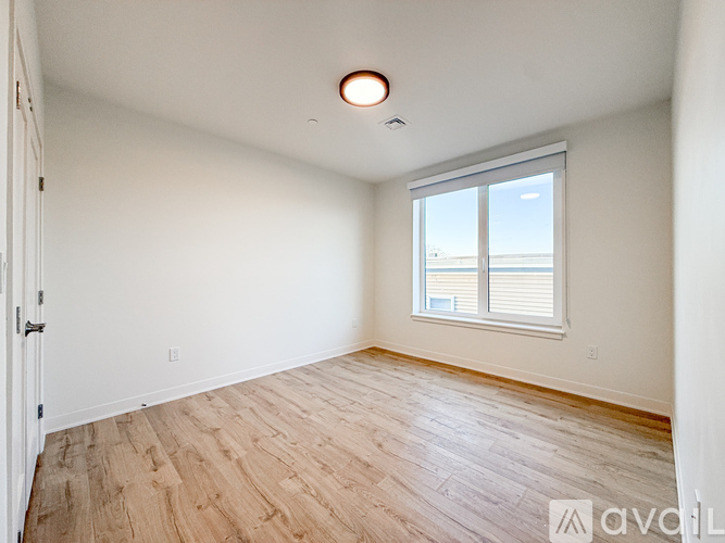 A spacious room with wooden flooring and white walls.