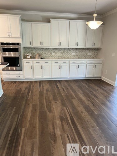 A kitchen with white cabinets and a wood floor.