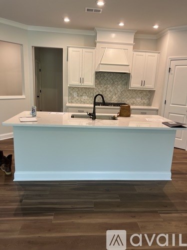 A kitchen with a white island and wooden floors.