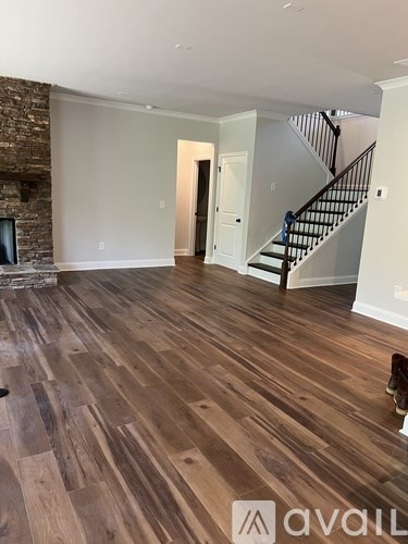 A room with wooden flooring and a staircase.