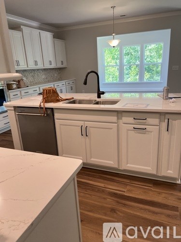 A kitchen with white cabinets and a marble countertop.