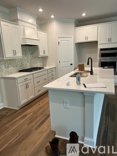 A kitchen with white cabinets and a wooden floor.