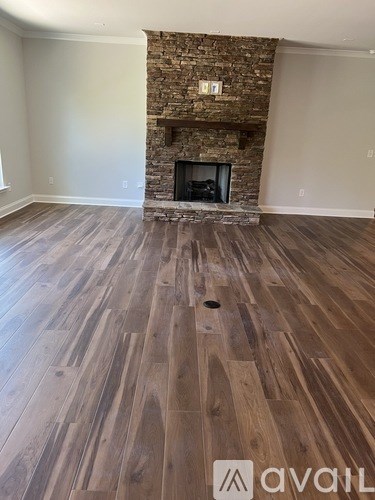 A room with a stone fireplace and wood flooring.