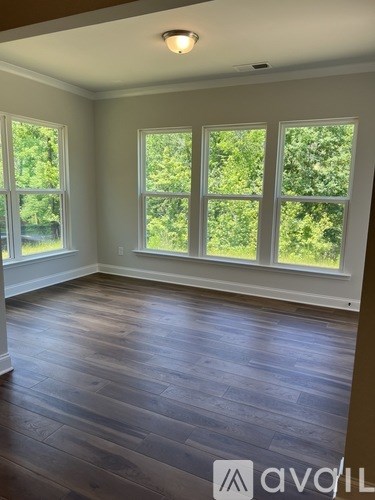 A room with wooden floors and three windows.