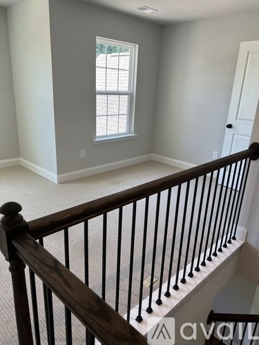 A room with a window and a wooden staircase.