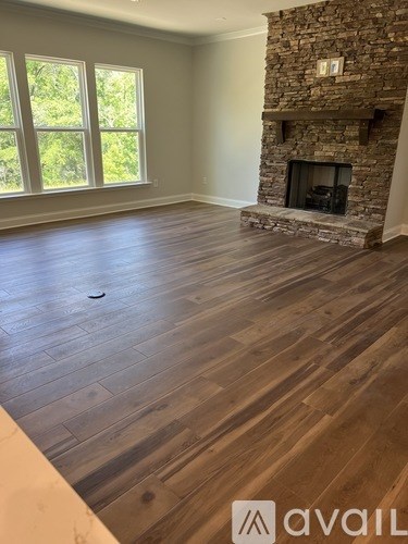 A room with a stone fireplace and wood flooring.