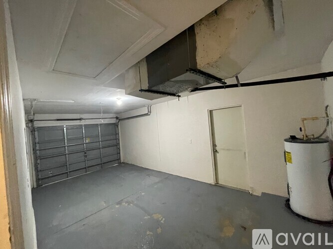 A room with a white wall, a door, and a white container on the floor.