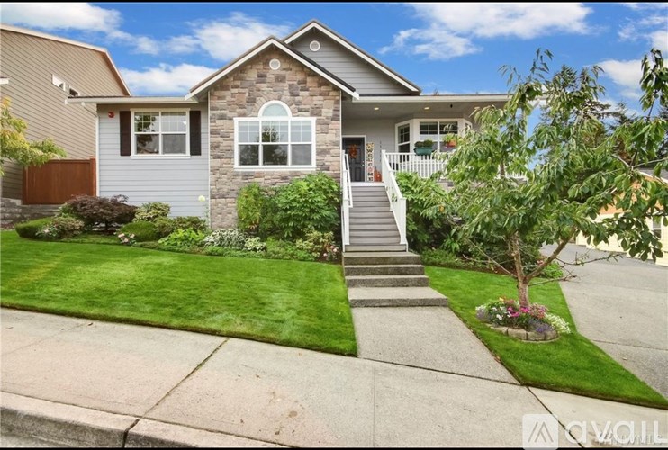 A house with a grey front and a tree in the front yard.