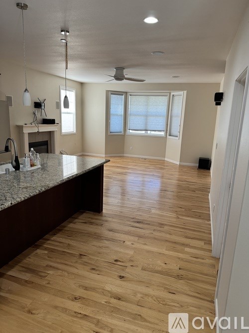 A spacious kitchen with wooden floors and a marble countertop.