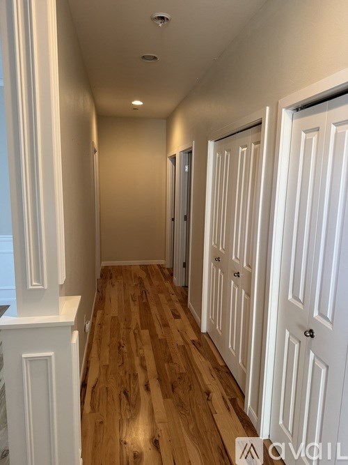 A hallway with white doors and wooden floors.