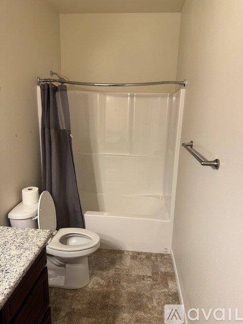 A bathroom with a toilet, a shower curtain, and a shower curtain rod.