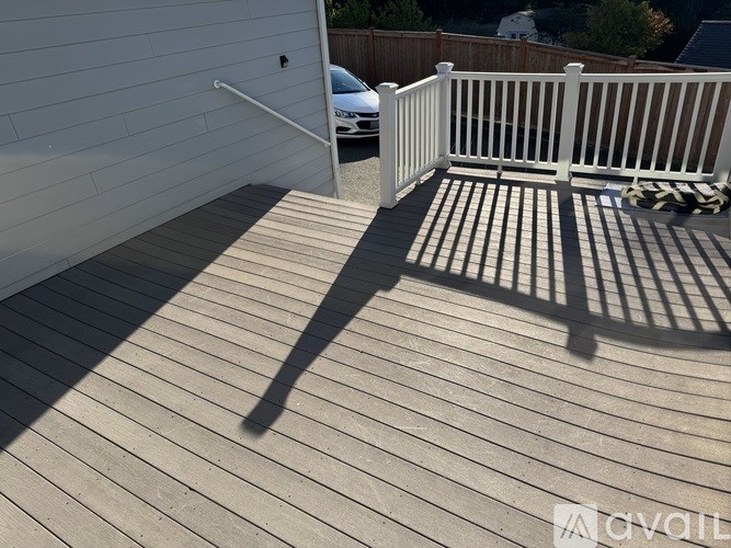 A deck with a white railing and a shadow of a person on it.