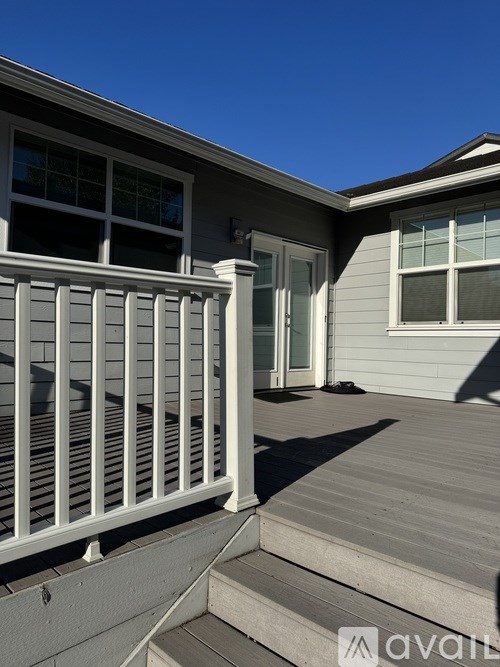 A house with a white railing and steps leading to a door.