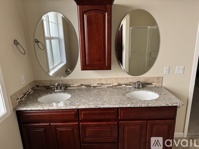 A bathroom with a granite countertop and two round mirrors.