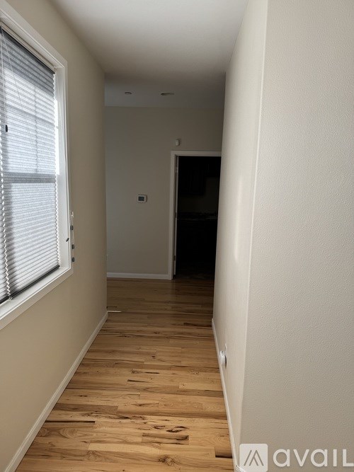 A hallway with wooden floors and white walls.