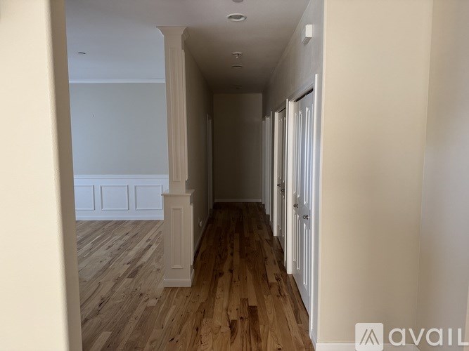A hallway with wooden floors and white walls.